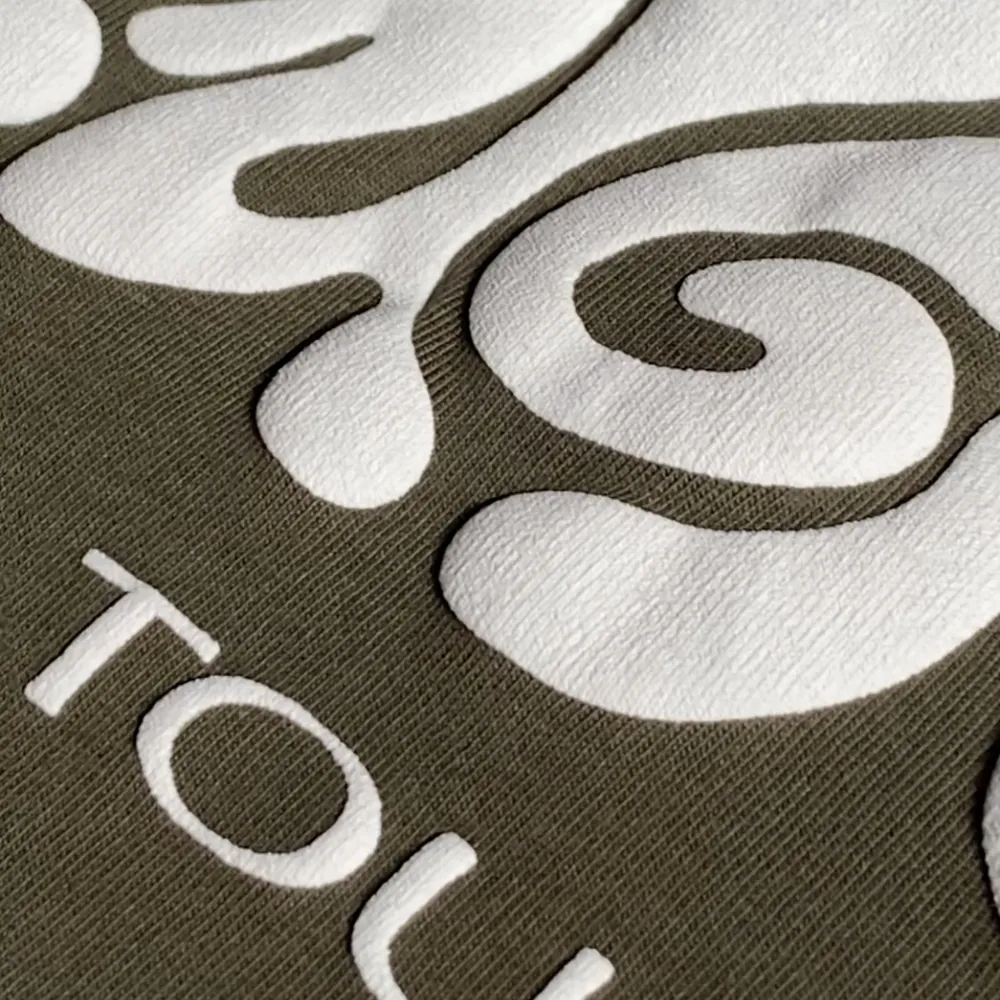 Wei&szlig;er 3D-Puff-Siebdruck auf olivgr&uuml;nem Stoff, Detail