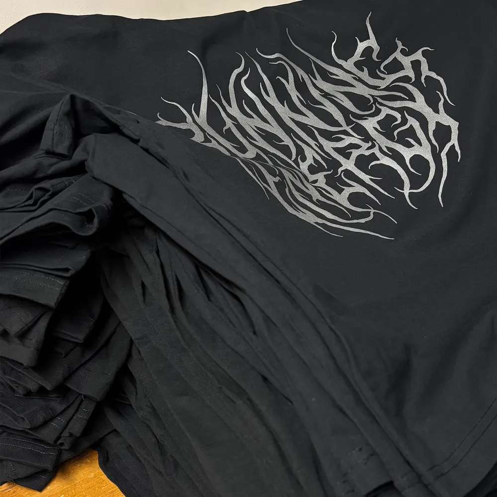 Stapel schwarzer Shirts mit reflektierendem Siebdruck